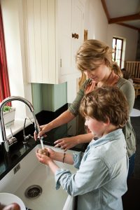 Mother and son washing potatoes in kitchen sink