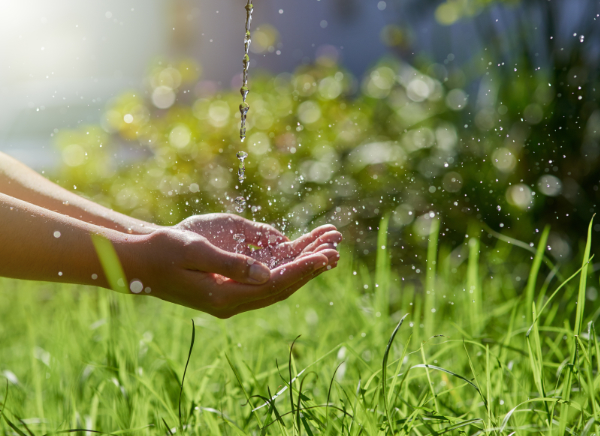 Shot of hands held out to catch a stream of water outside